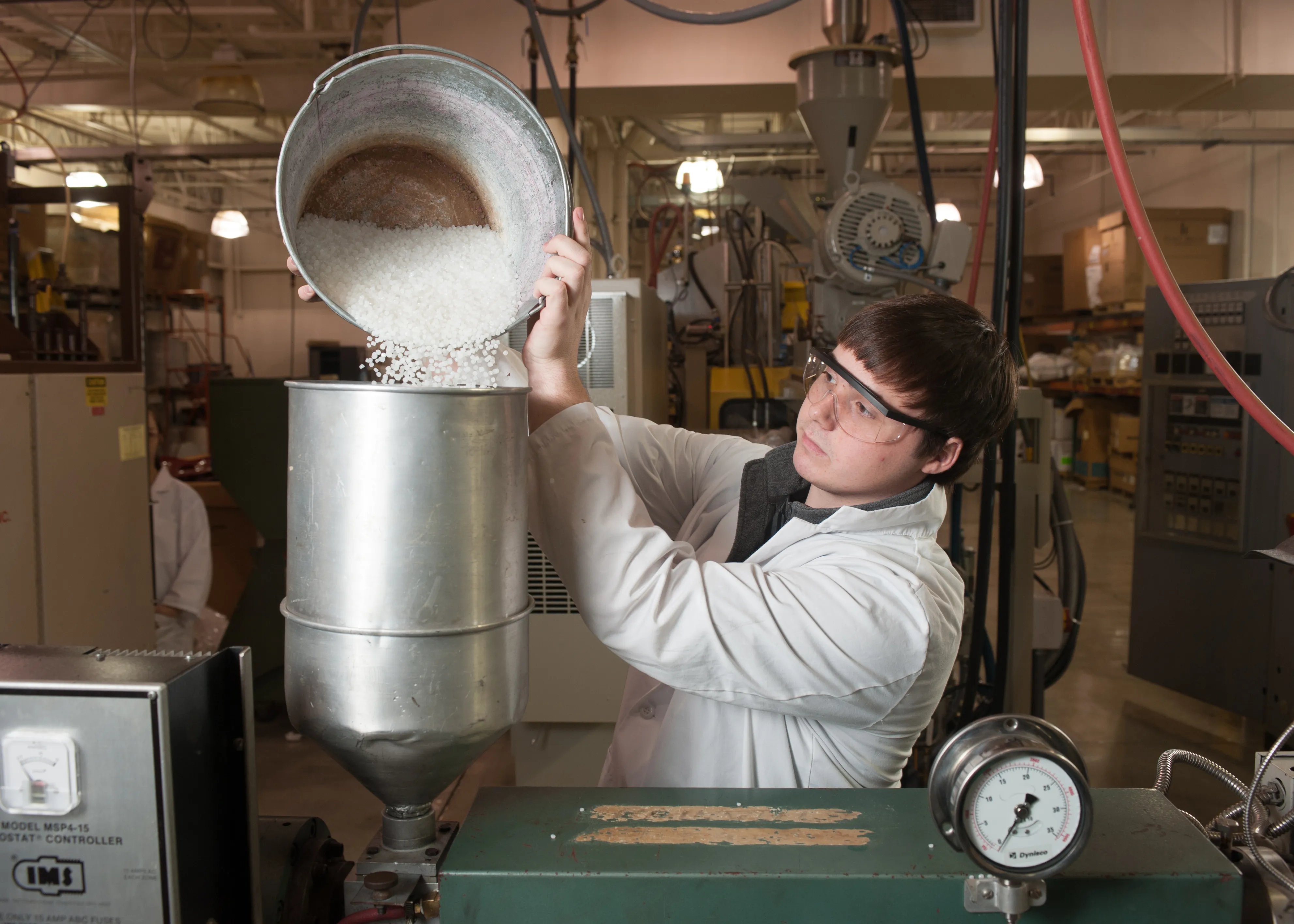 student pouring plastic pellets into a machine