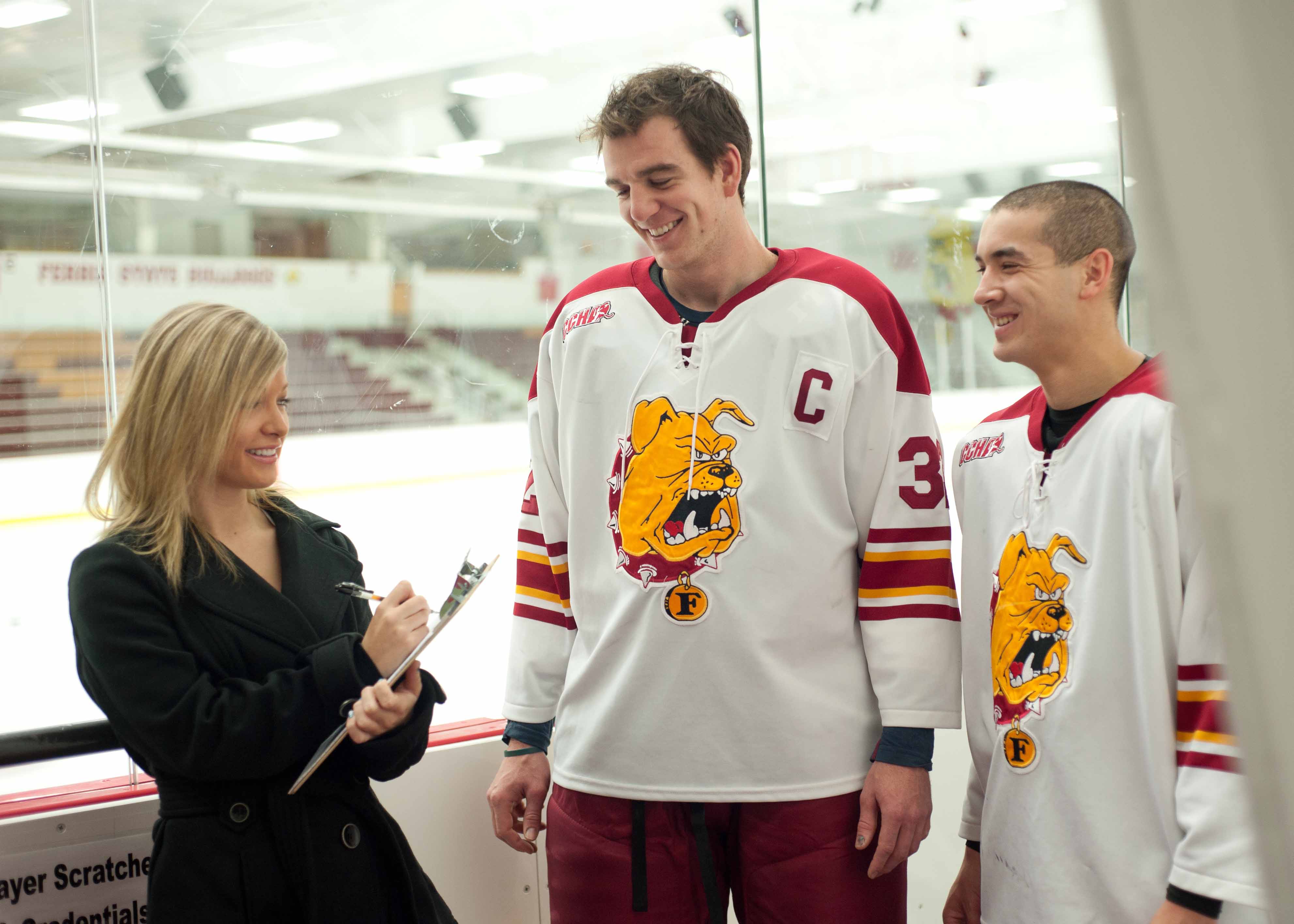 sports communication student interviewing two hockey players