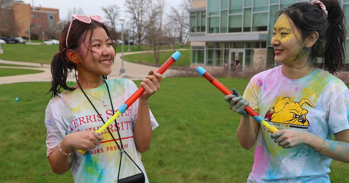 Ferris State University international students at color festival holding water squirters filled with colored water