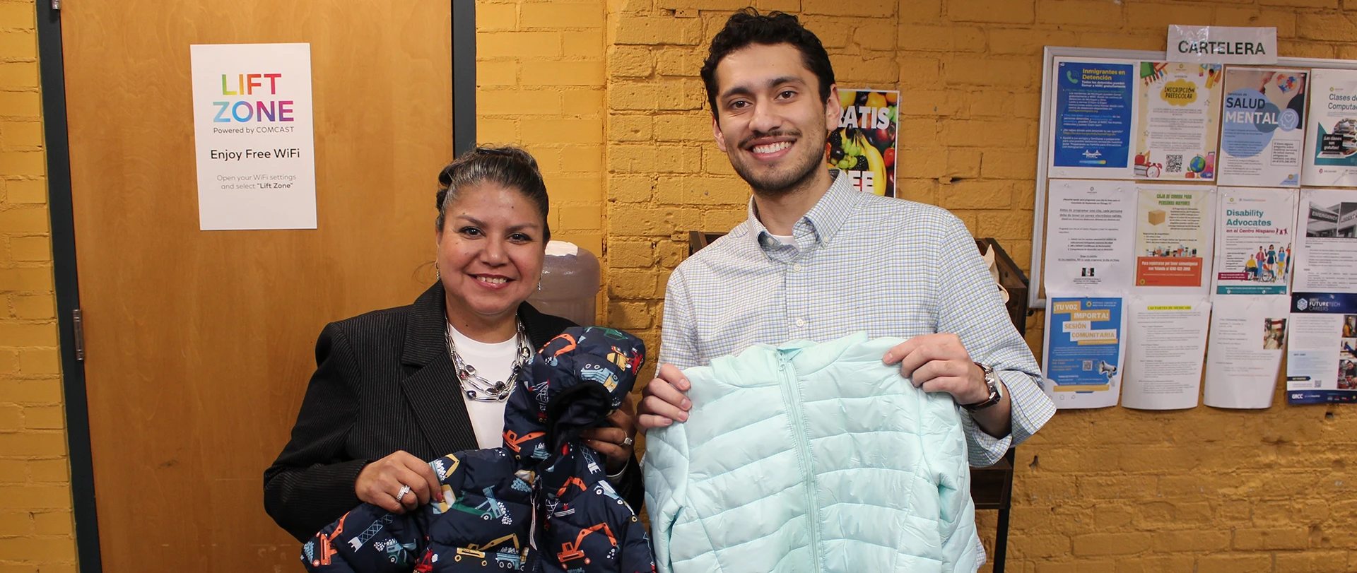 Sonia Trevino, Director of Ferris State's Hispanic/Latino Cultural Center and Eleazar Lopez-Diaz, Corporate Gift Officer at the Hispanic Center of West Michigan show of a few of the more than 700 coats collected for West Michigan families.