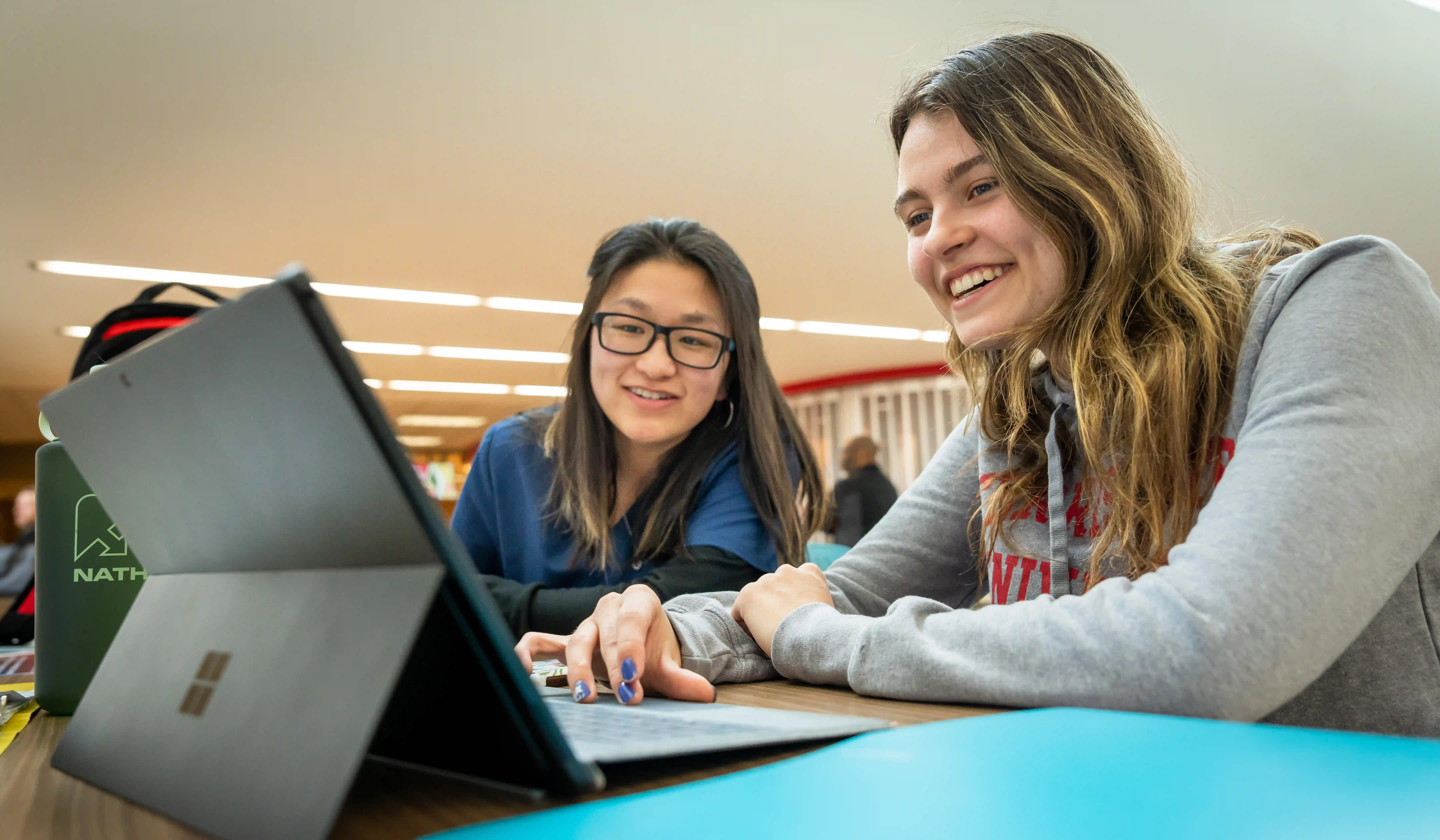 Two students smiling working on a computer