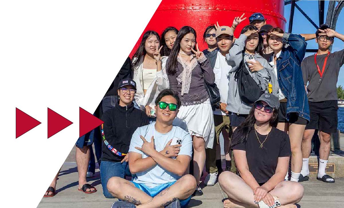 A group of Ferris State University international students sitting on a lighthouse pier overlooking Lake Michigan.