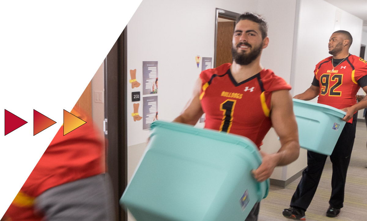 Student atheletes carrying boxes into residence halls on move in day at Ferris State University