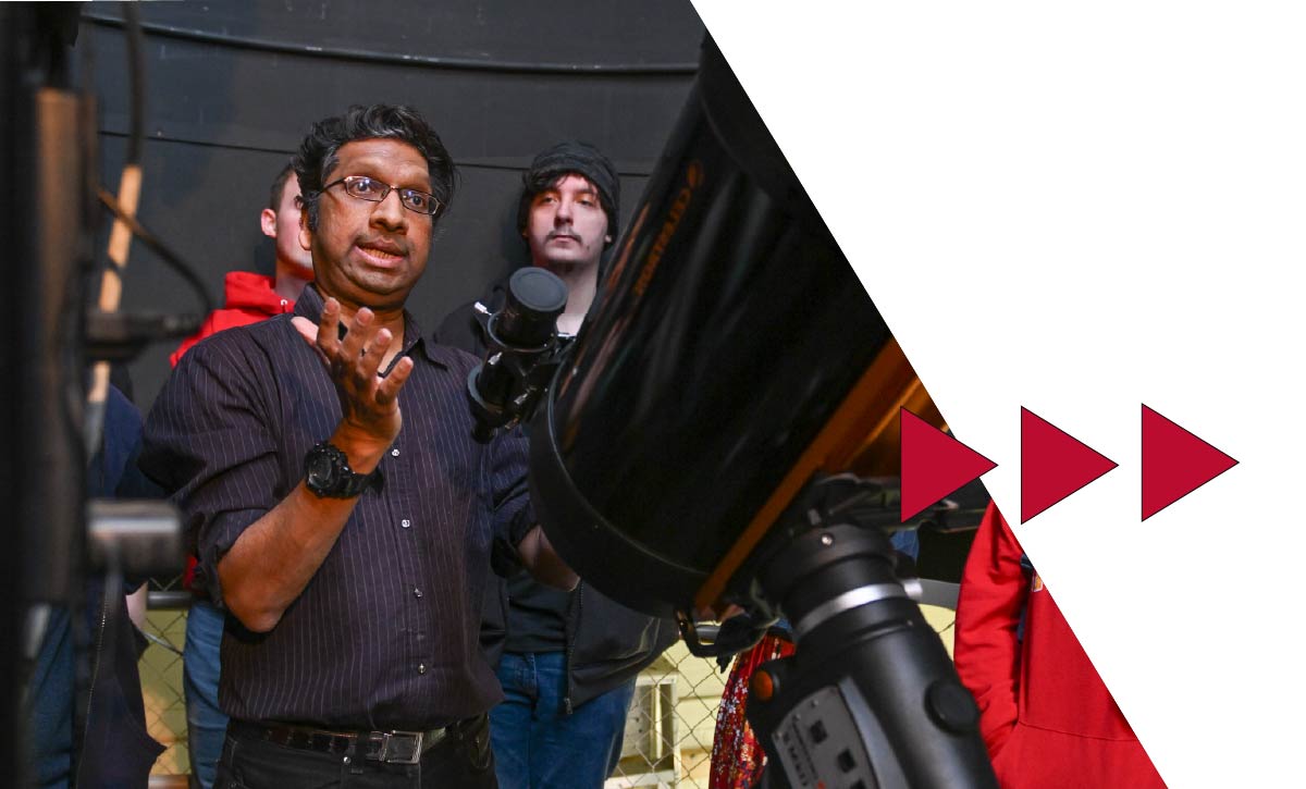 a professor using a telescope with a group of students