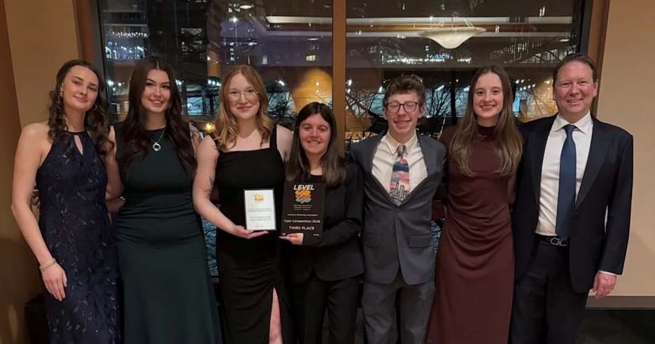 Students holding their award plaques while standing with professor Mike Levins (far right)