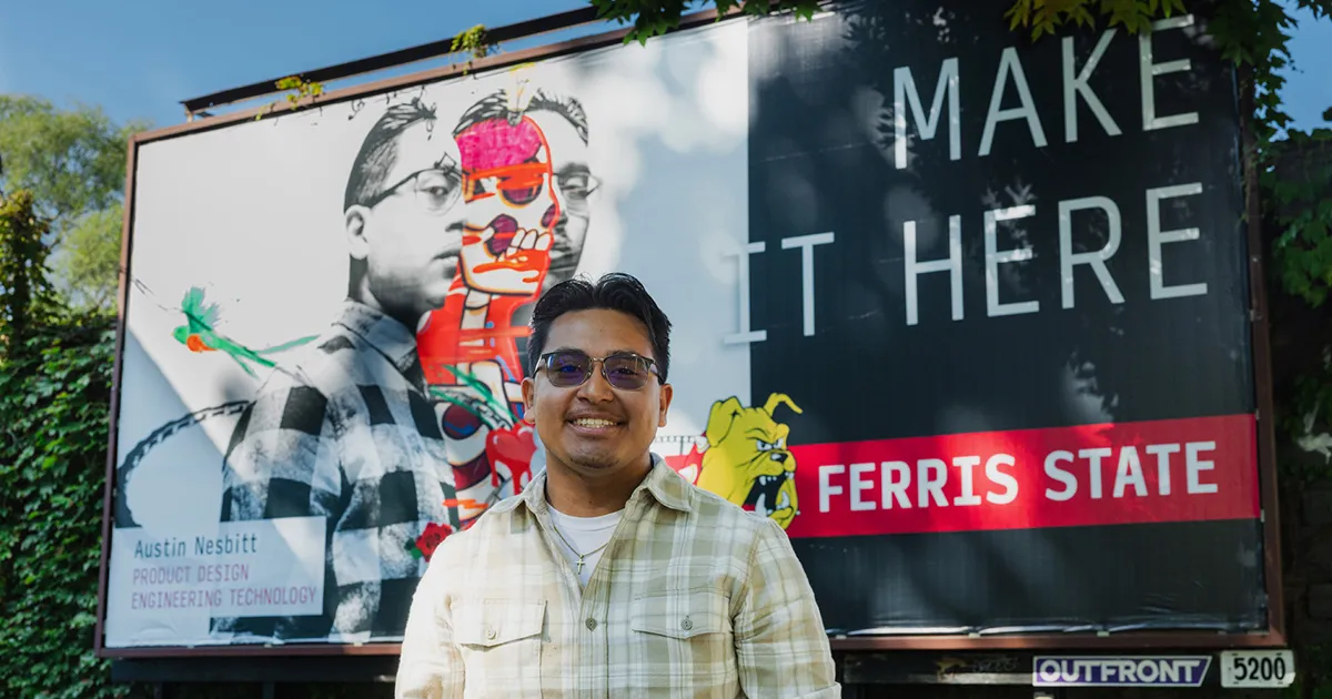 student standing in front of a billboard with his artwork on it