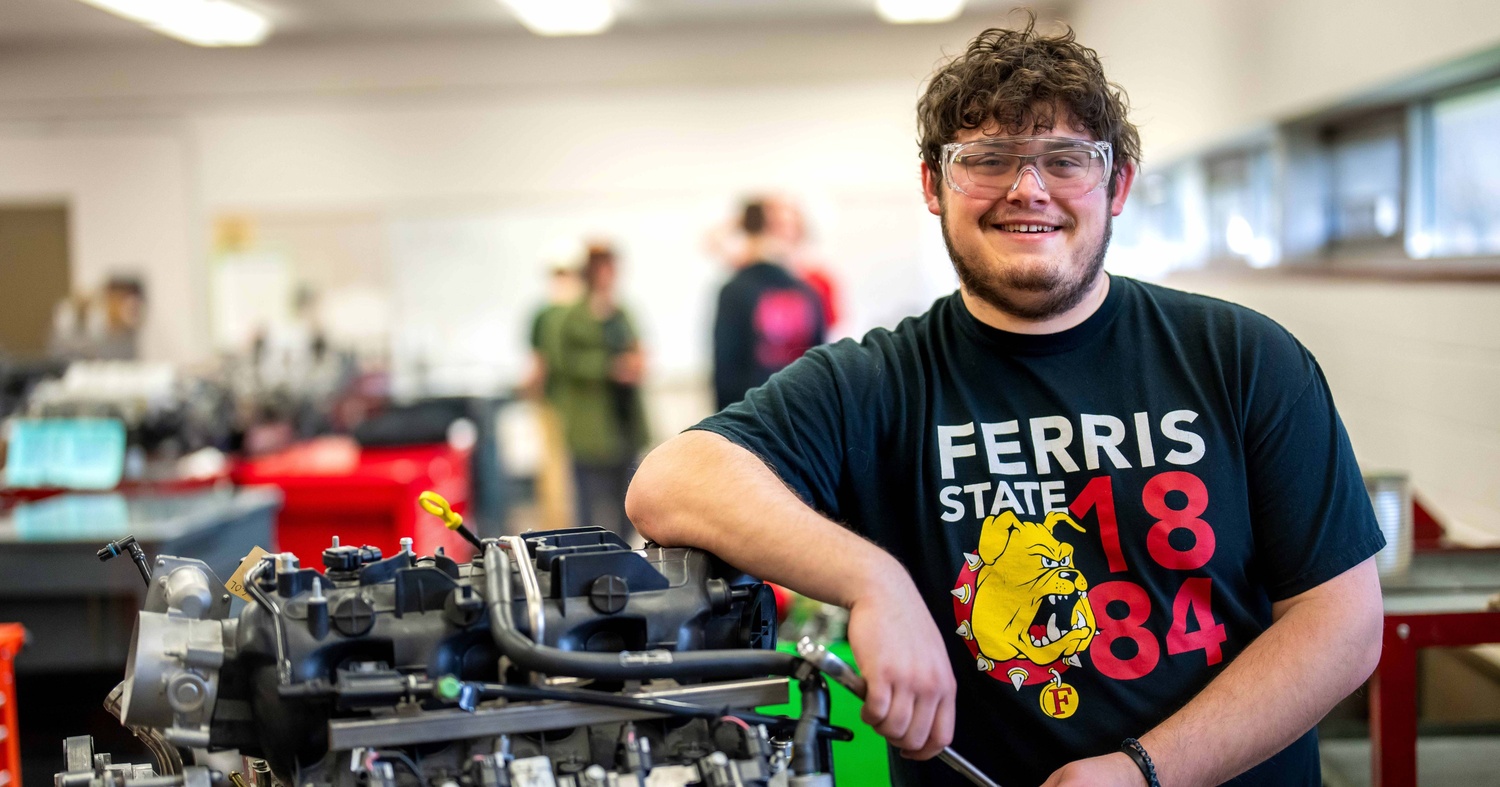 Photo of an automotive student working on an engine during a classroom lab.