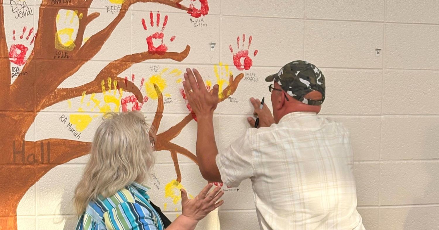 The Beitner's leaving their handprints and name on the tree mural in Hallisy Hall