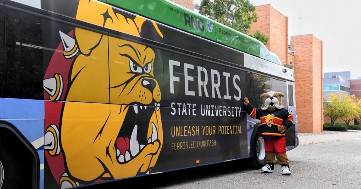 brutus mascot standing next to a bus branded with ferris state