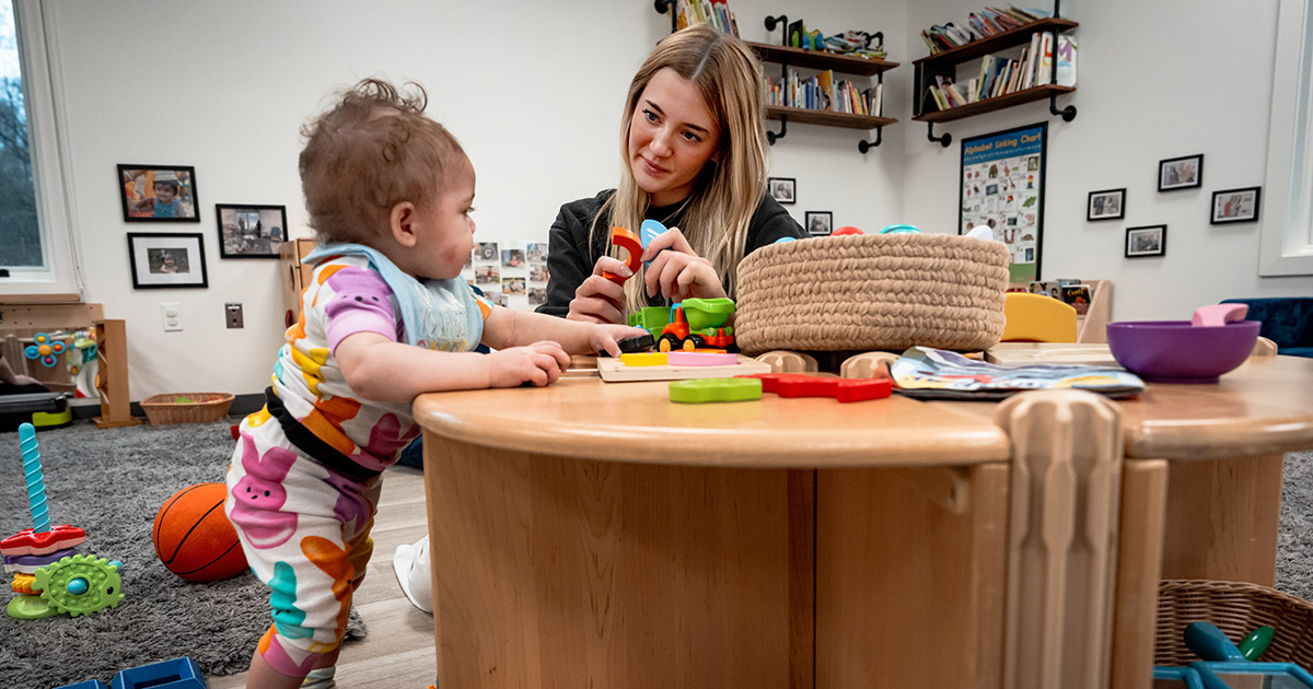 an early childhood educator working with a child in a classroom