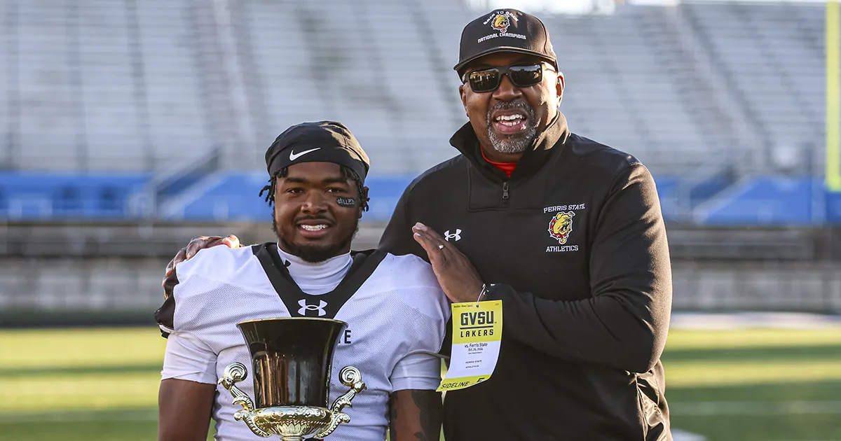 two people holding a trophy celebrating a football win