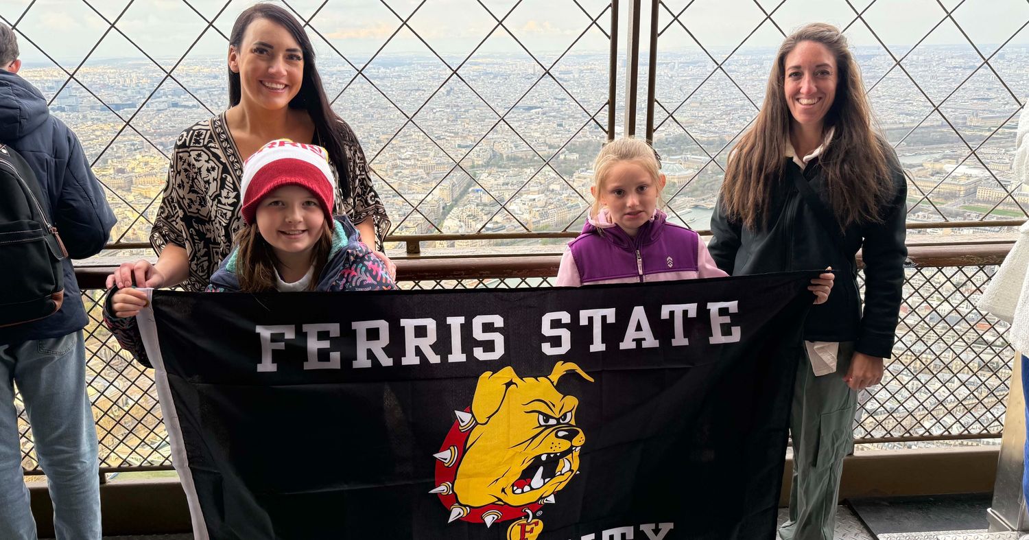 Puruleski standing with her daughter holding a Ferris State University flag while on top of the Eiffel Tower in Paris, France