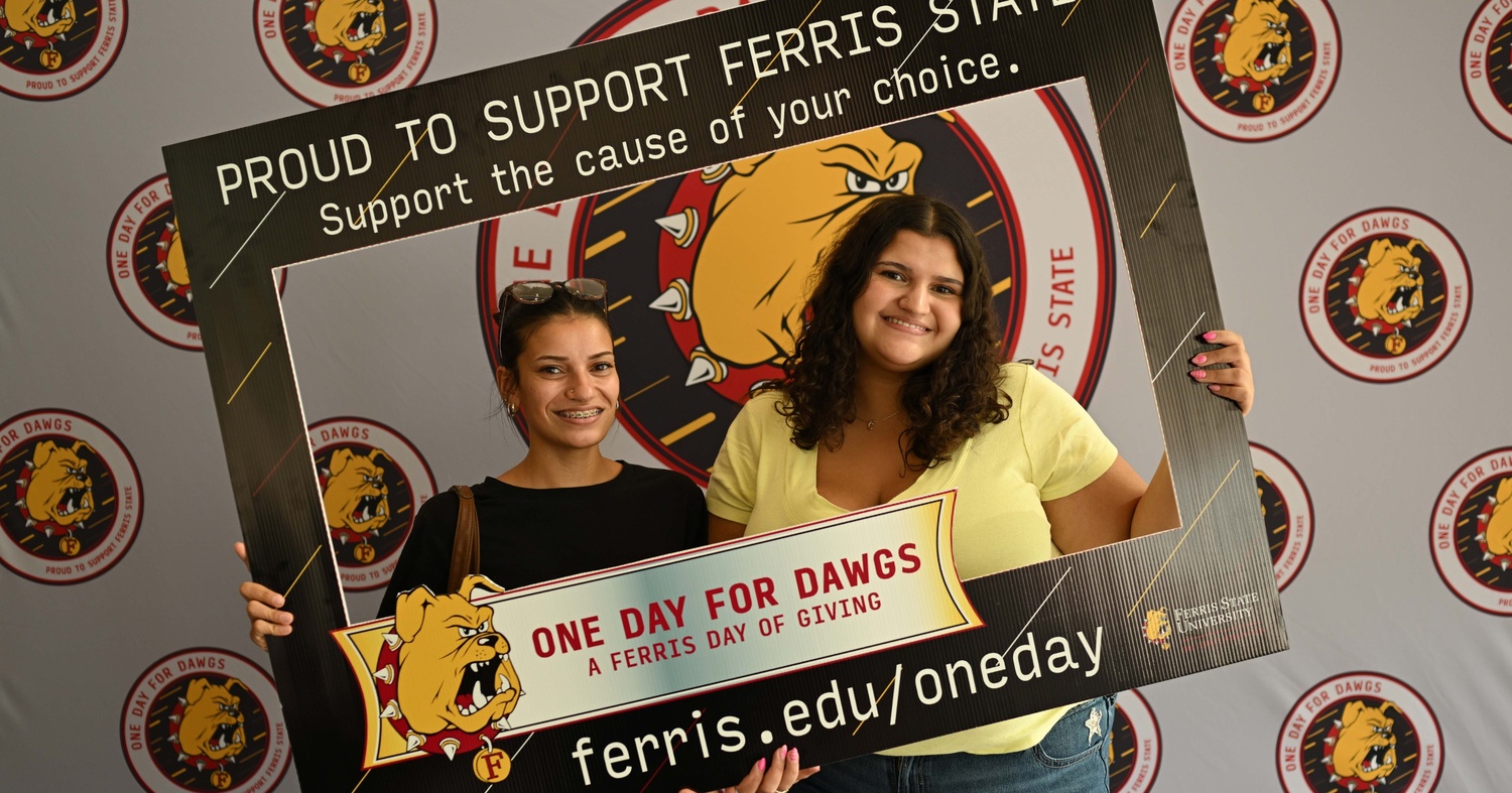 Students posing with a One Day for Dawgs portrait cutout