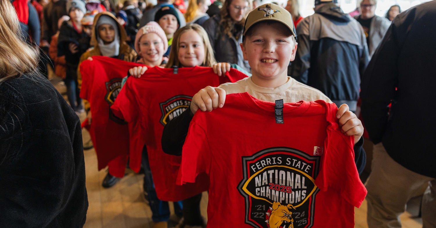 Students from nearby elementary schools joining the Bulldog Spirit Day fun while holding up championship t-shirts