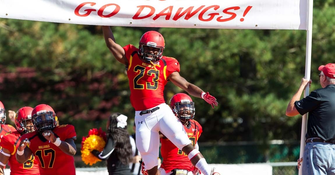 Kit Clark jumping up to tap a banner reading "Go Dawgs" while the Ferris State football team runs onto the field for a matchup against Ashland University in 2016
