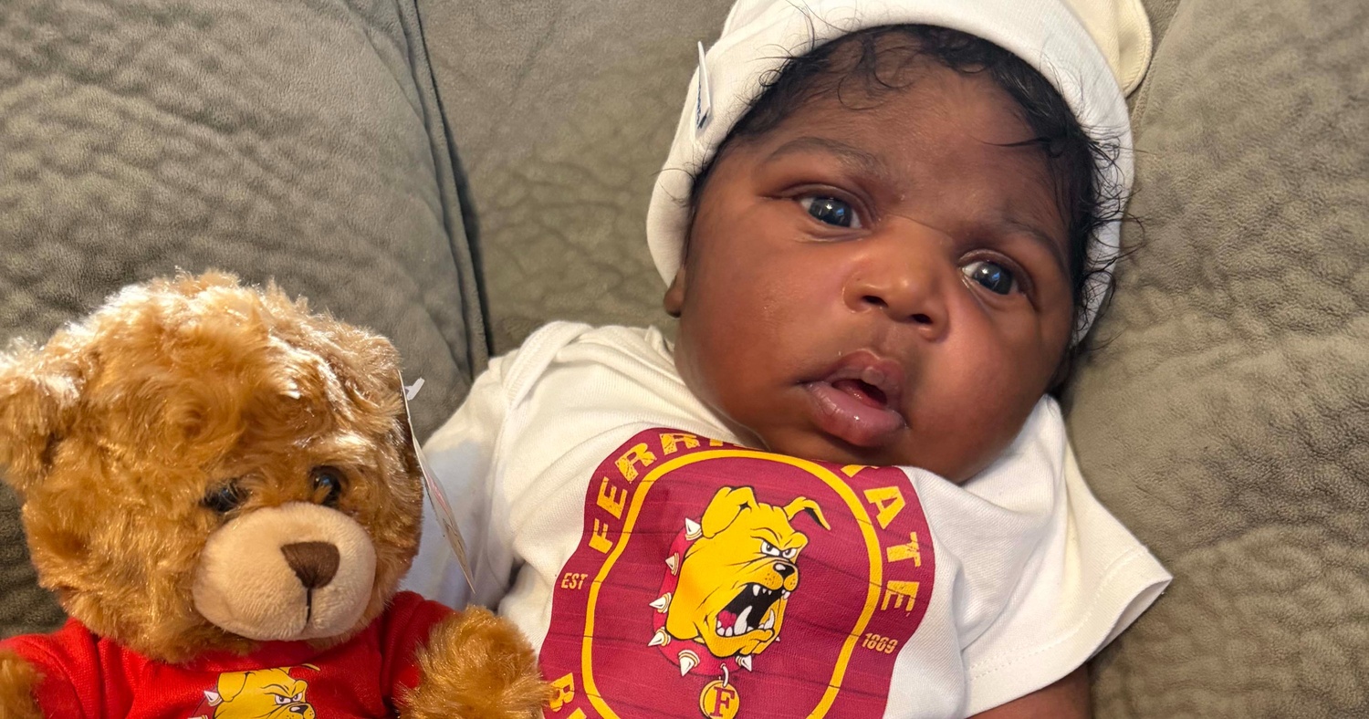 Baby Ferris representing the Bulldogs with his outfit, accompanied by a Ferris State teddy bear