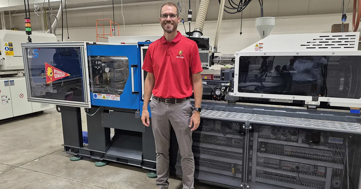 faculty standing next to an injection molding machine