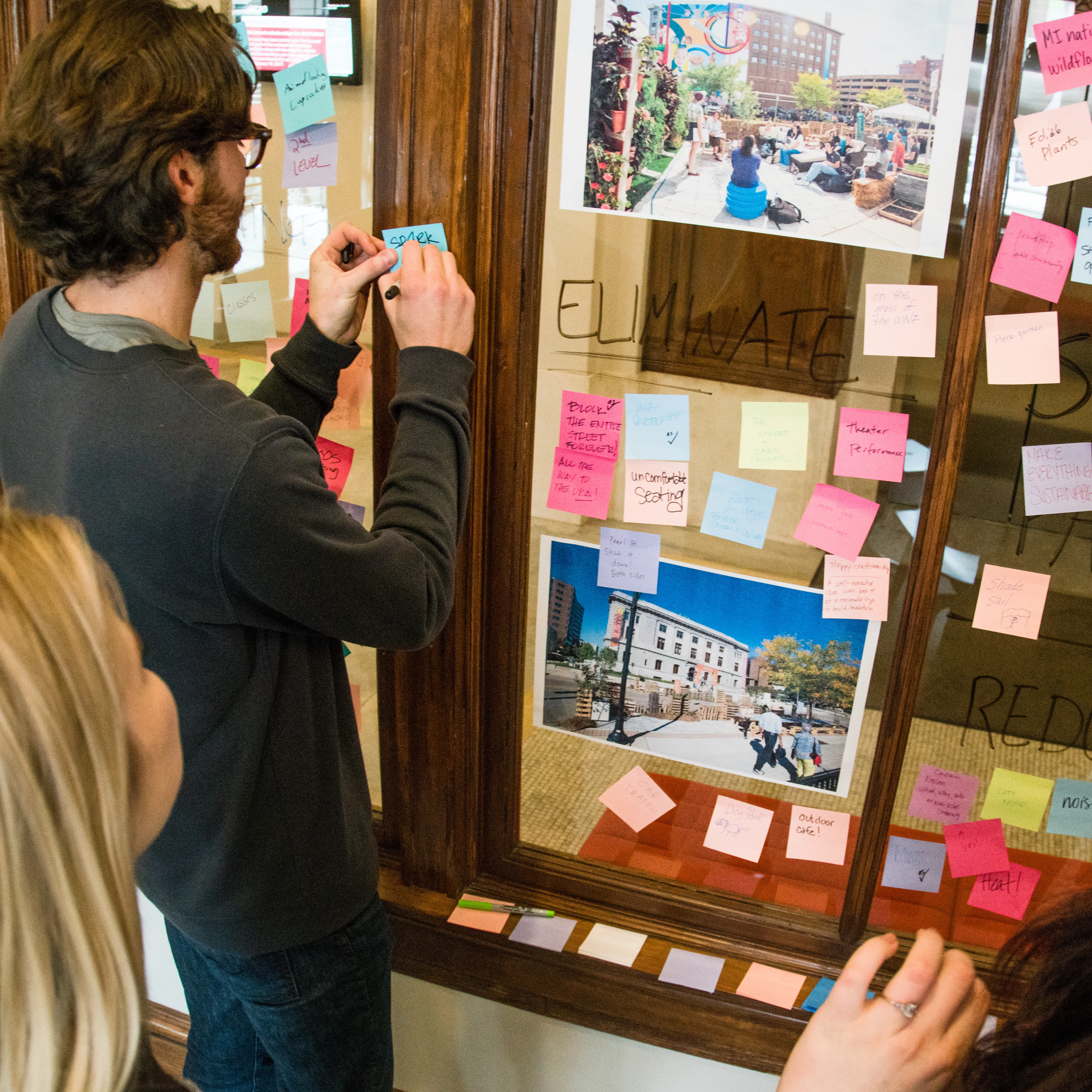 students brainstorming with sticky notes on glass