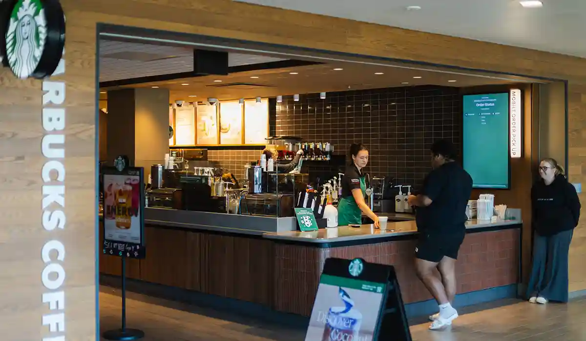 Starbuck's employee handing a student their drink order.