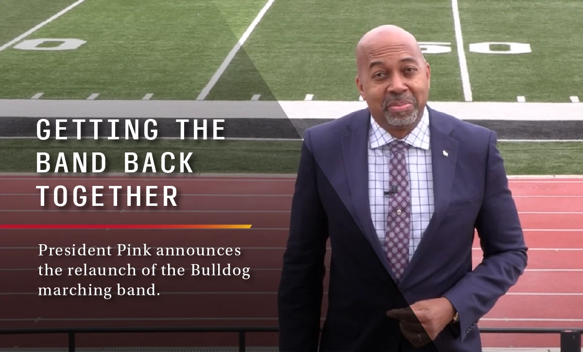 President Bill Pink standing in the bleachers at the Ferris State University football field with a text overlay that reads, "Getting the band back together - President Pink announces the relaunch of the Bulldog marching band."