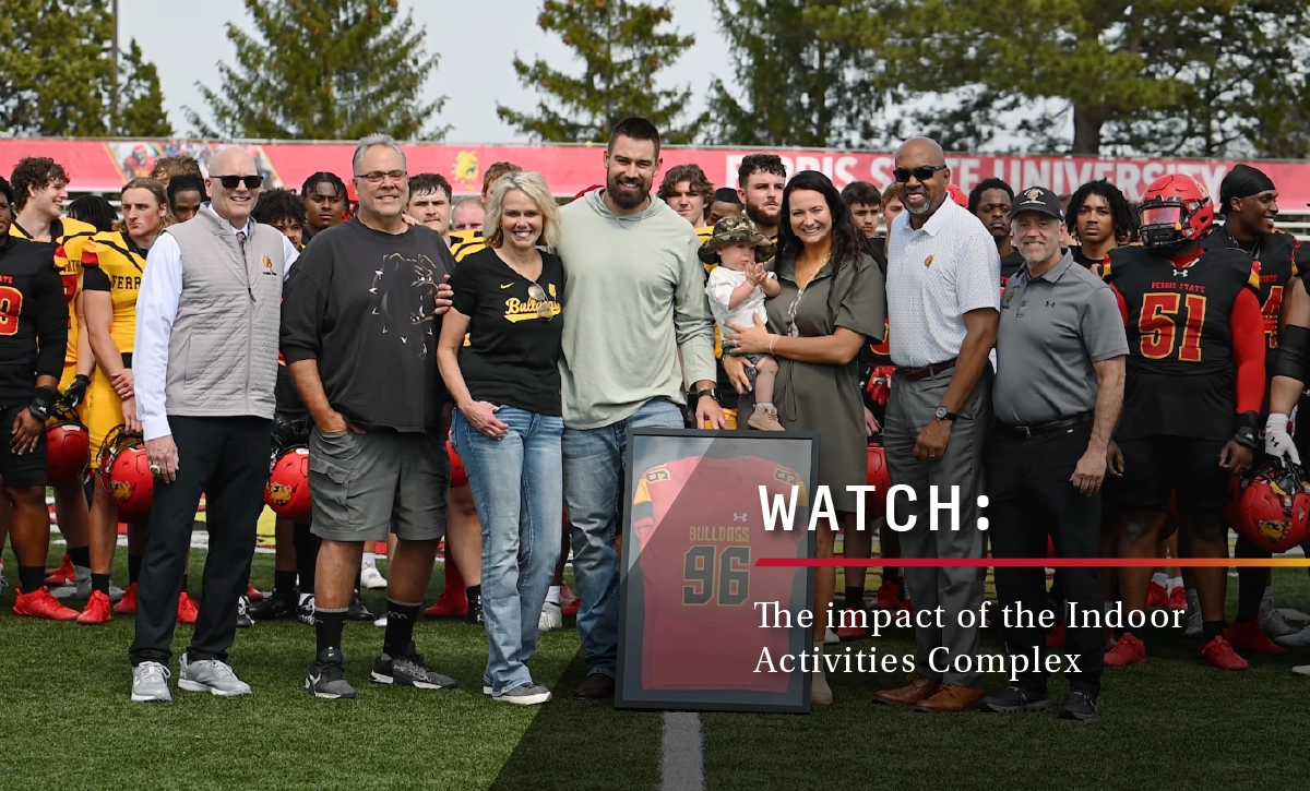 large group shot on Ferris State's football field with a framed bulldogs jersey in the forefront
