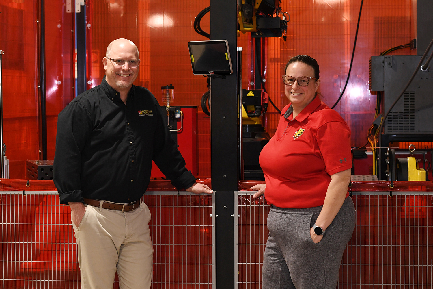 Bill Koepf, Angie Mishler posing  in front of equipment in the Ferris State College of Engineering Technology. 