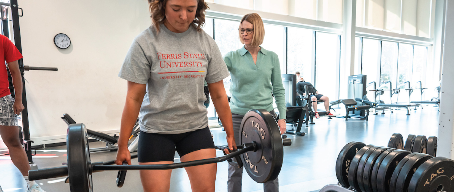 Student lifting weights with an instructor in the class.