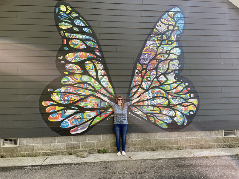 Katlyn Sheldon posing in front of a butterfly mural