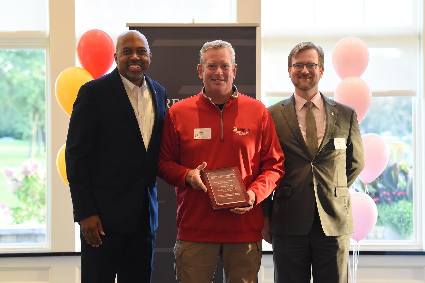 MCO Alumnus of the Year 2022 Dr. Bradley Taylor received his award plaque from FSU President Dr. Bill Pink and MCO Dean Daniel Taylor .