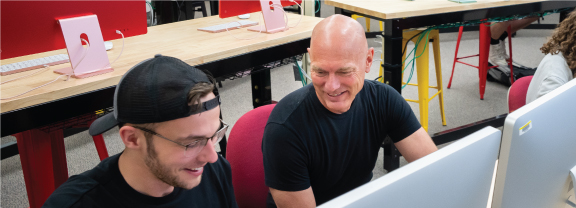 Student and professor working on a laptop.