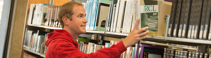 Student grabbing a book from GRCC's Library.