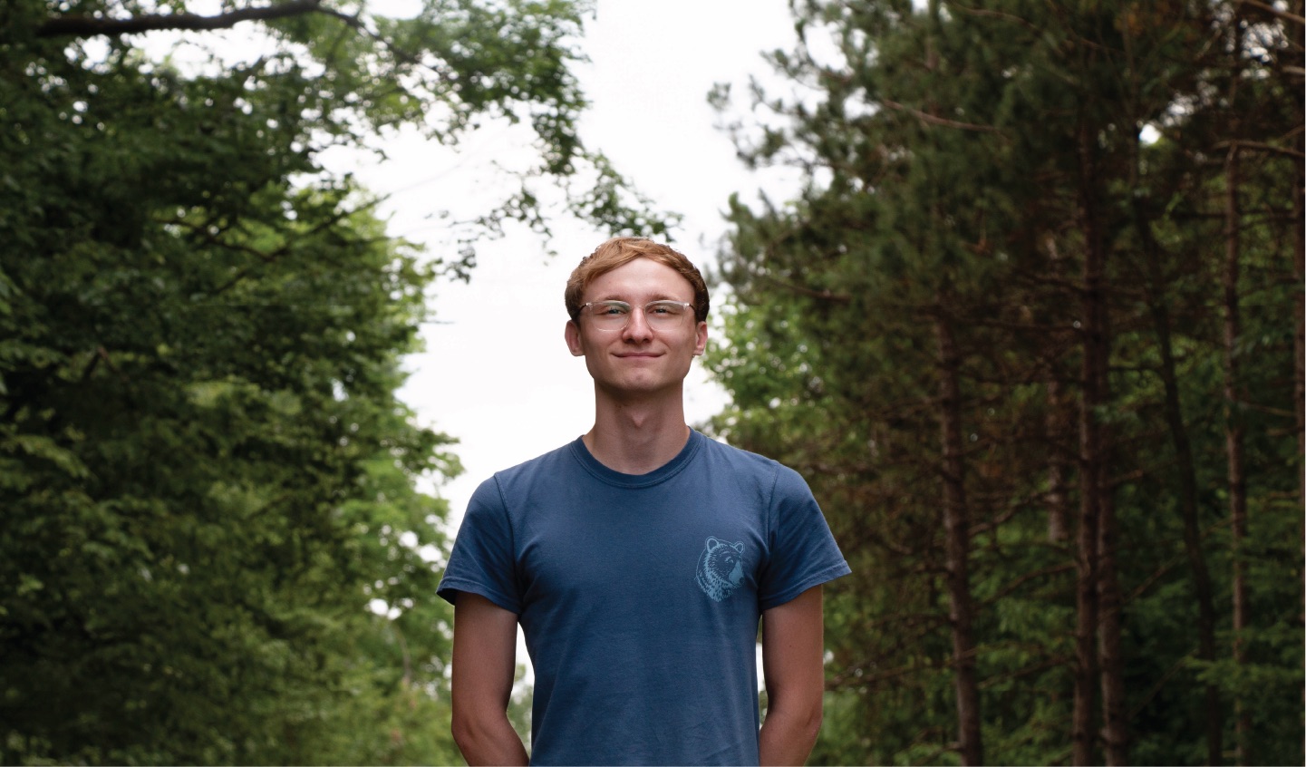 Student surrounded by trees.