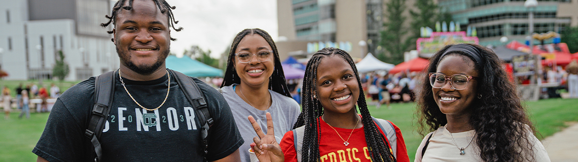 four students standing and smiling